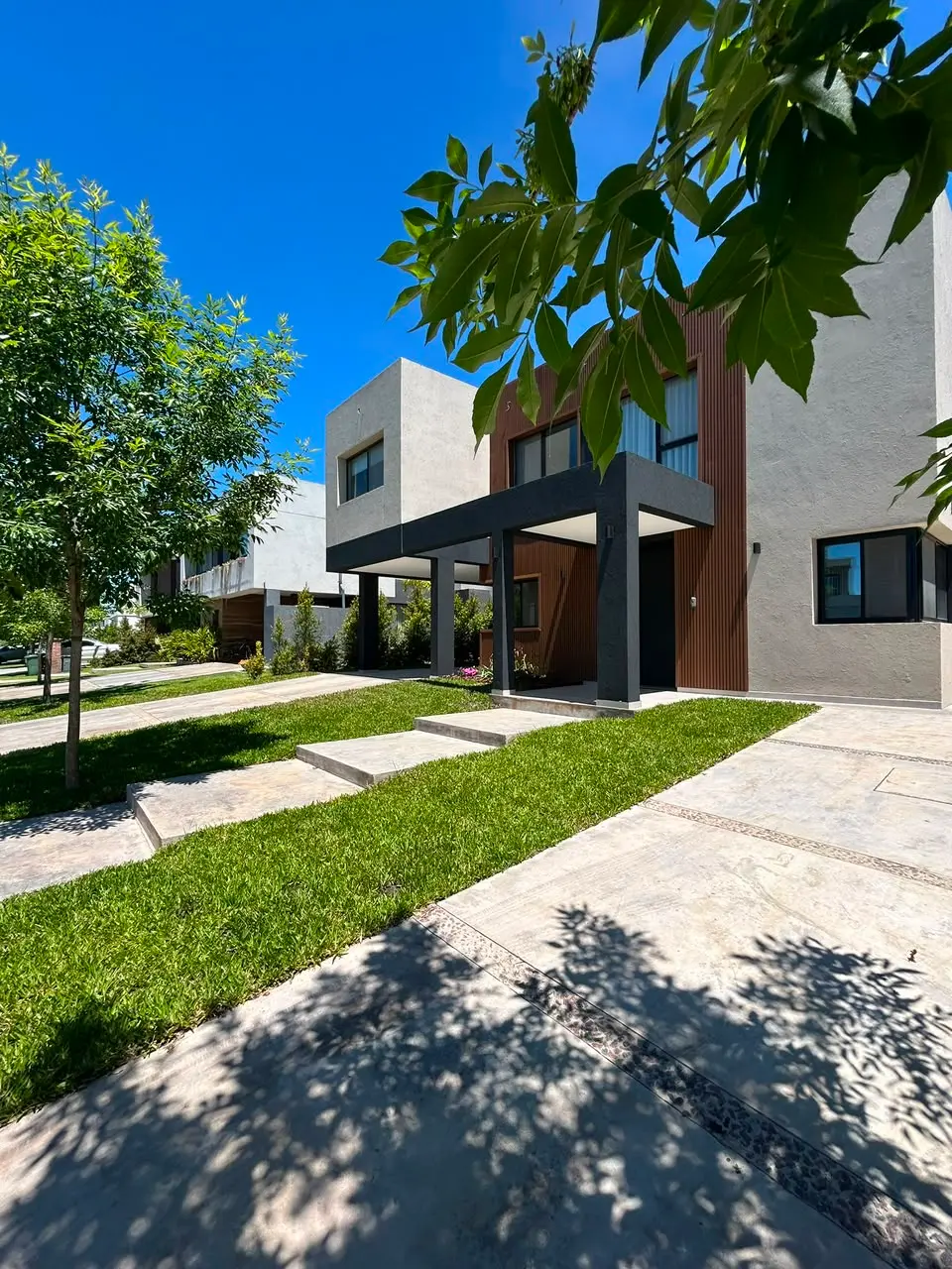Frente de casa moderna con césped y canteros en un barrio cerrado de Nordelta — proyecto de paisajismo
