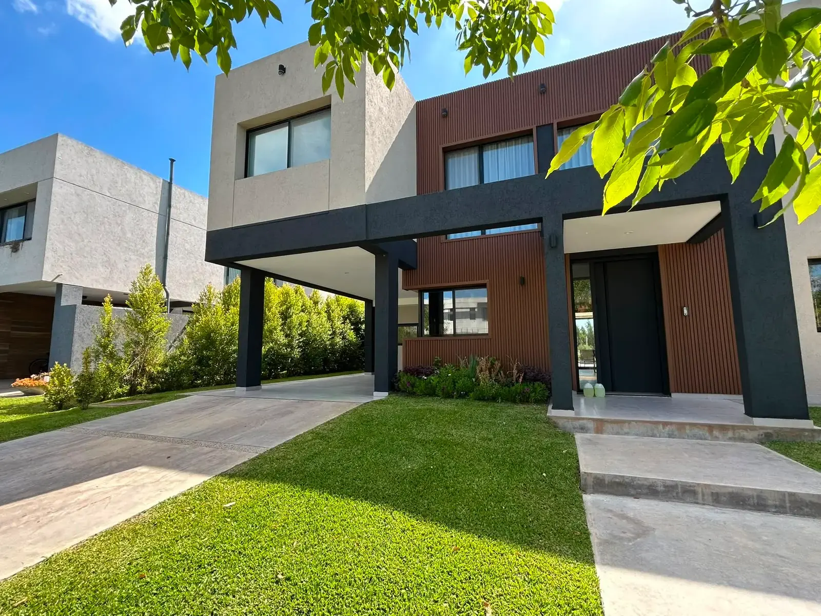 Frente de casa moderna con jardín, césped y canteros en un barrio cerrado de Zona Norte — proyecto de paisajismo integral